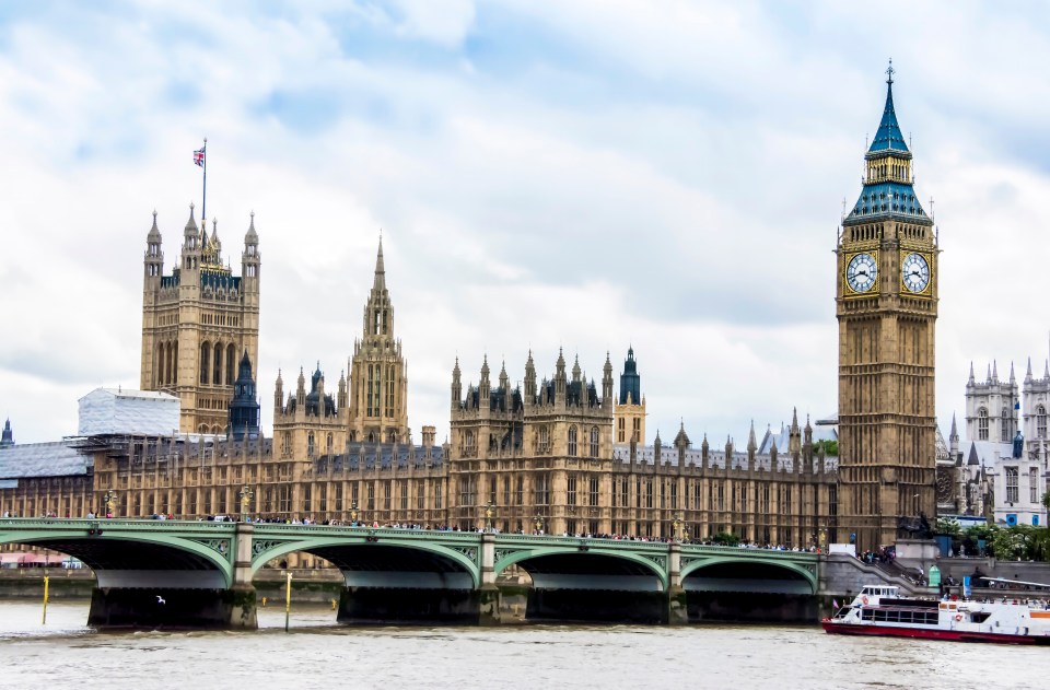 The Palace of Westminster and Elizabeth Tower in London, with a bridge over the Thames River in the foreground.